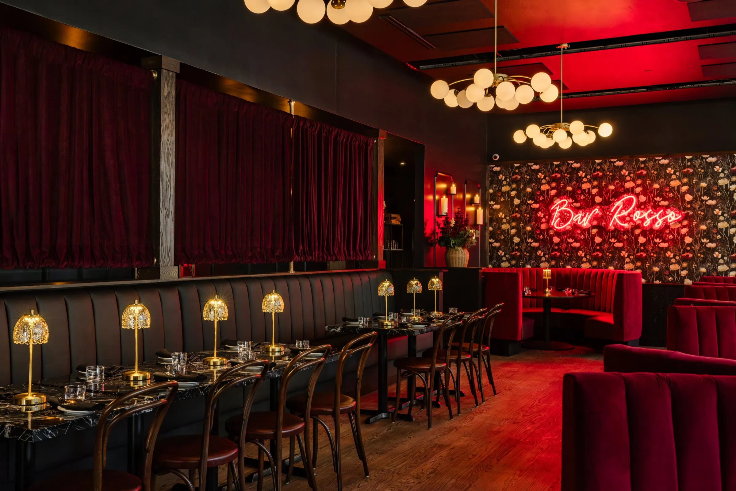 The Bar Rosso private dining room, with red velvet booths, brass lamps and the neon sign